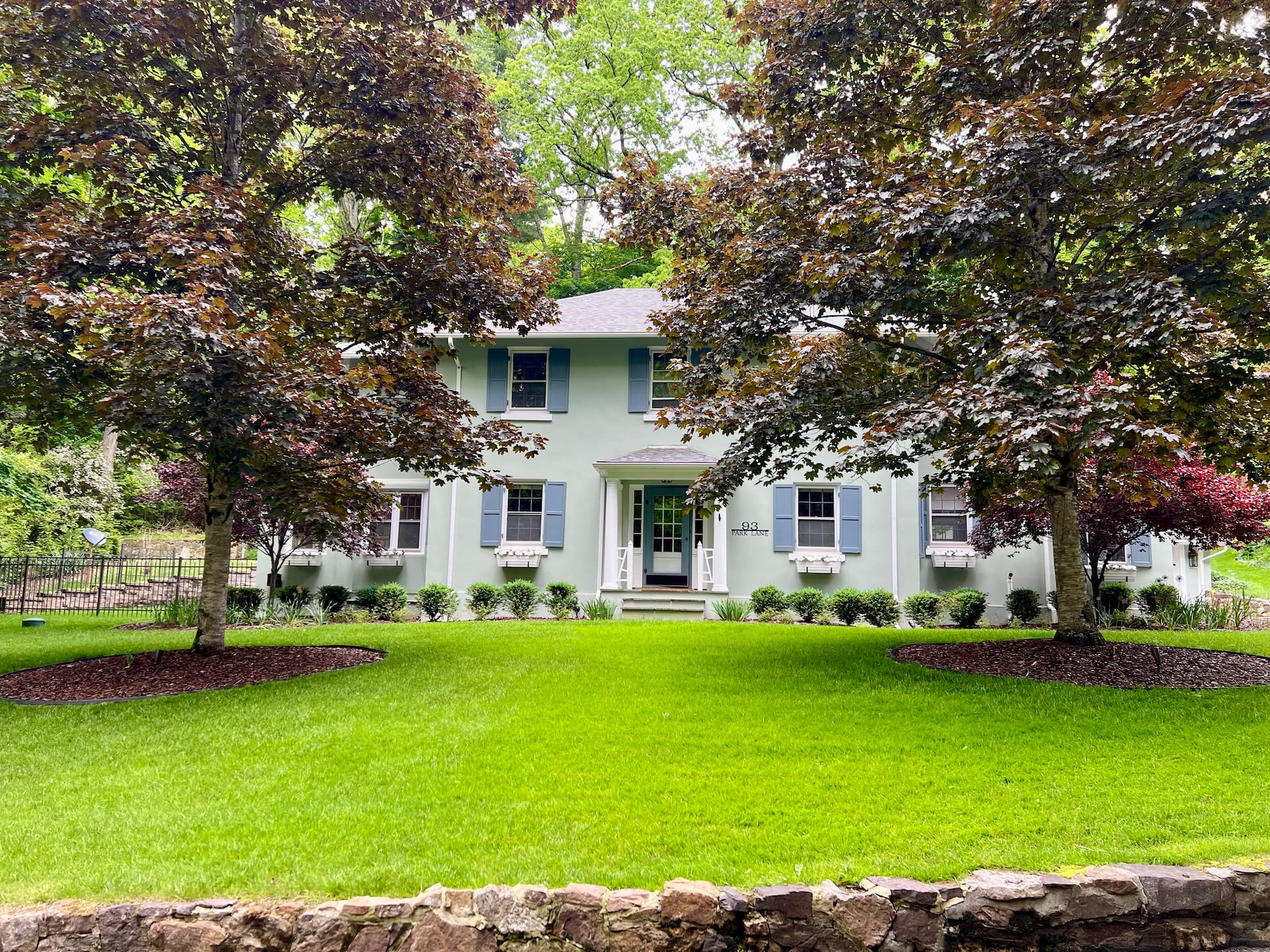Park Lane’s white historic house, framed by mature trees and a green lawn